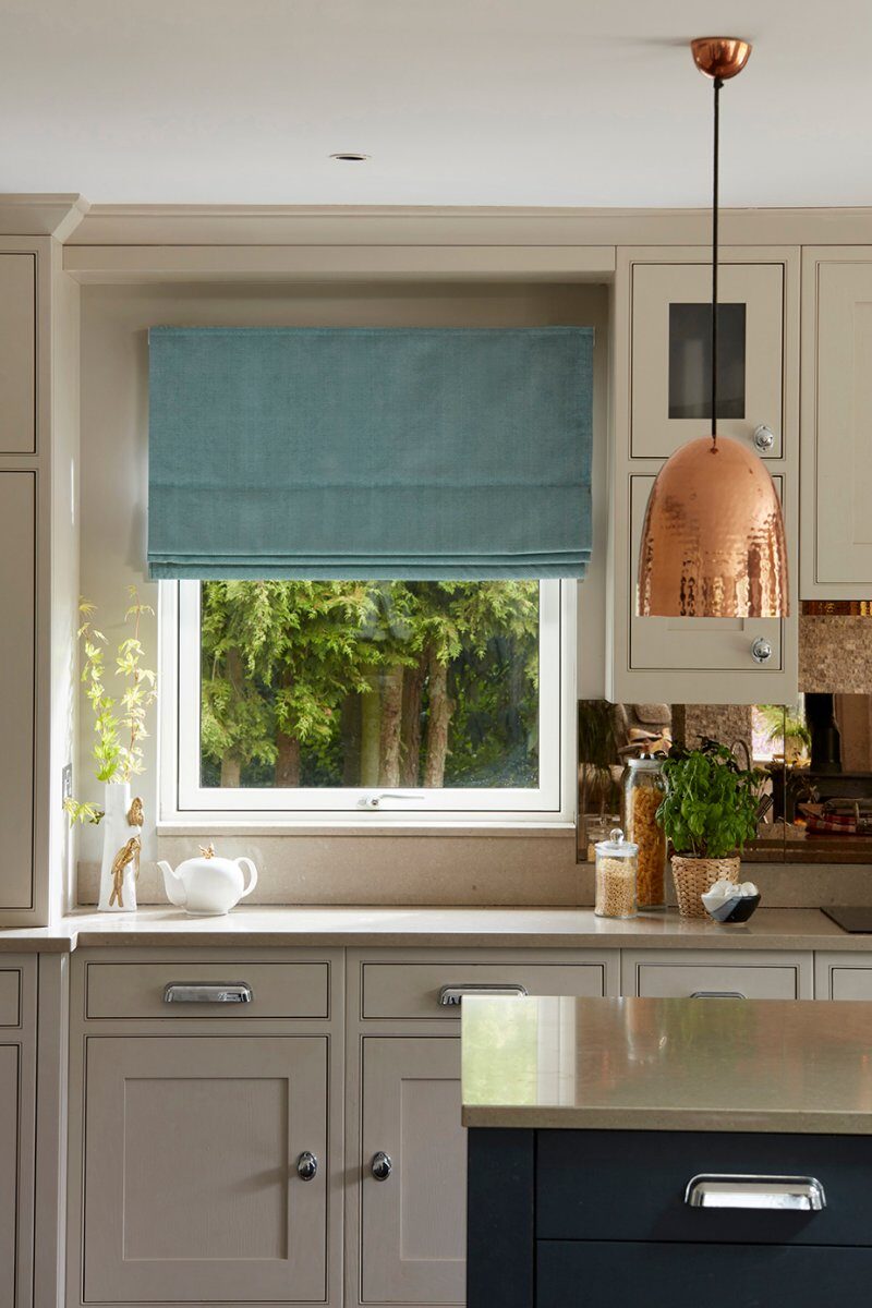 Teal roman blind above a kitchen sink with copper pendant