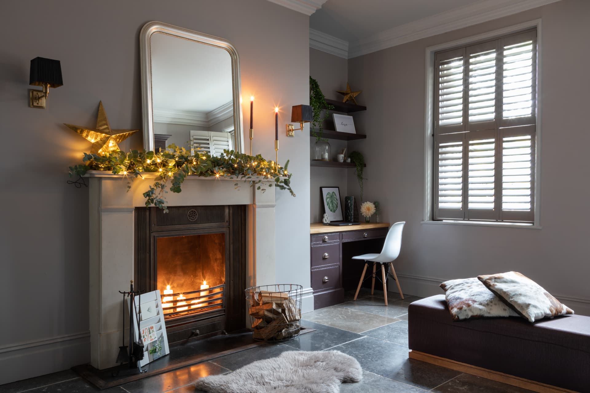 Stone coloured shutters in a living room with a lit fire