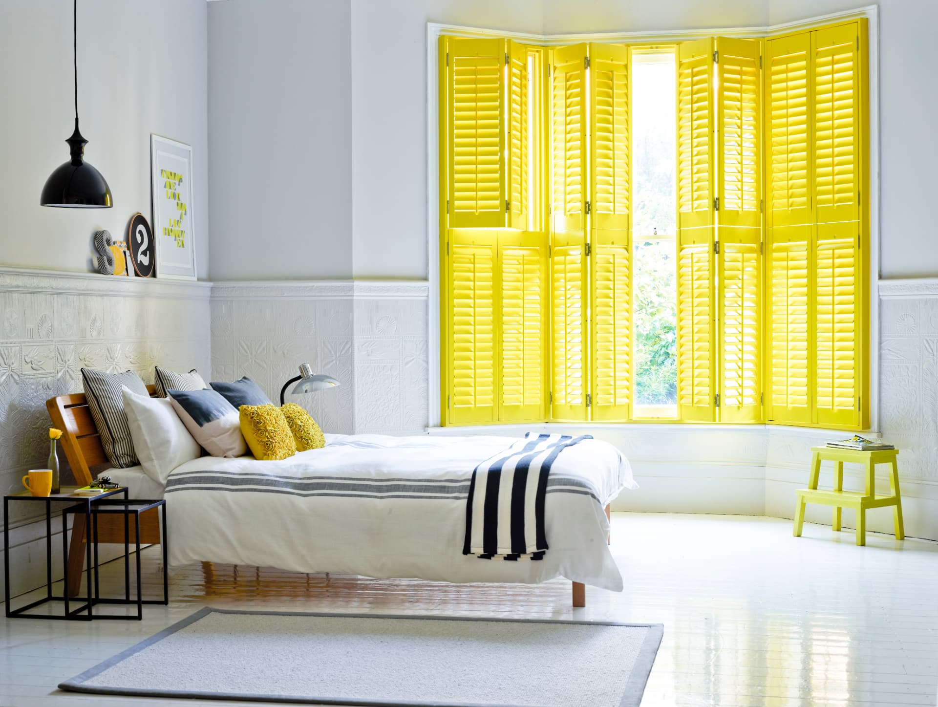 Bright yellow tier-on-tier shutters in a bedroom bay window