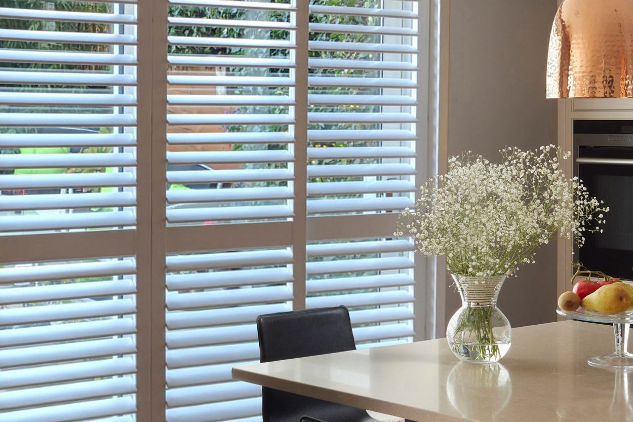 Close-up of white shutter louvres beside a dining table
