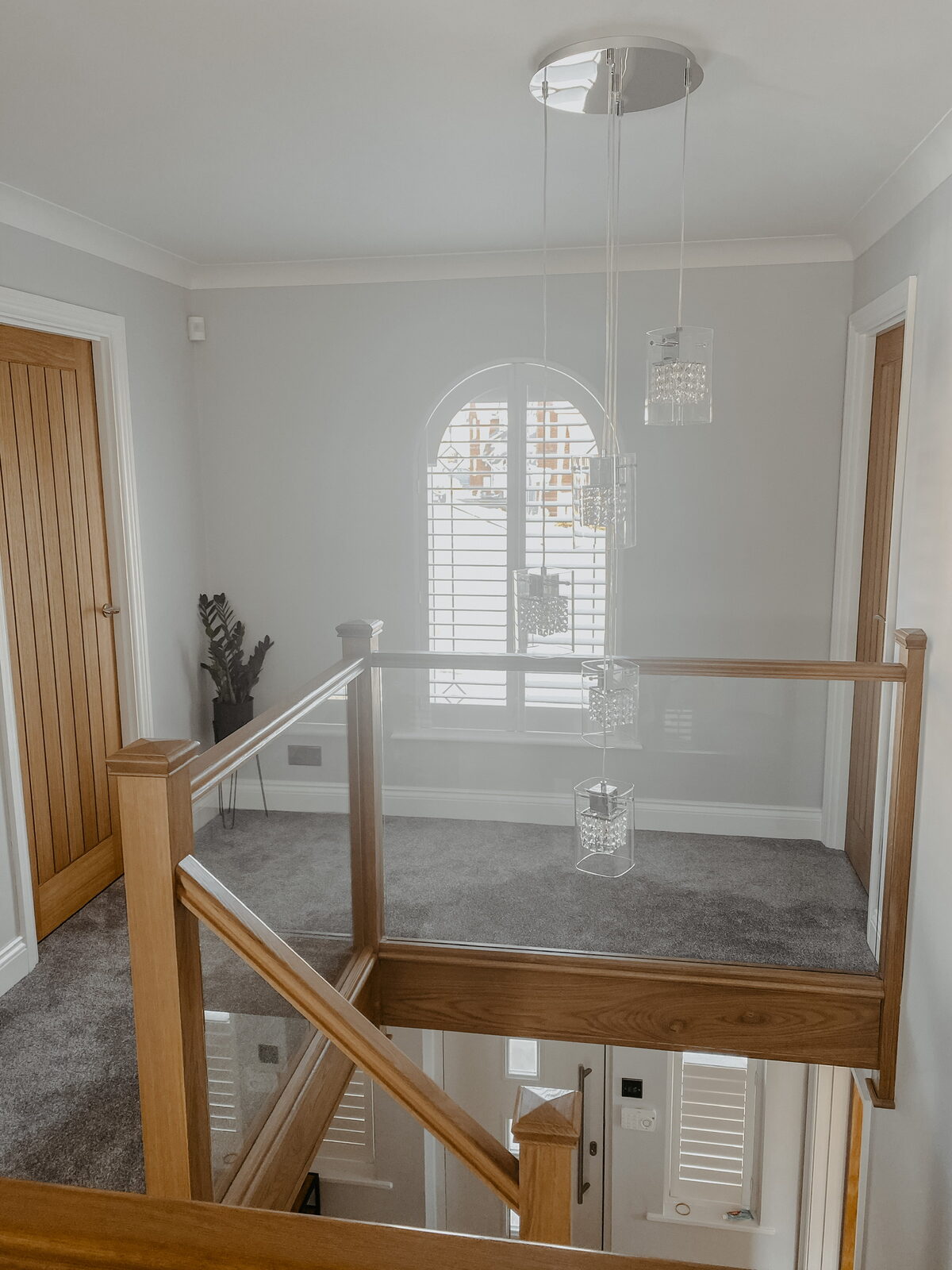 Shutters on an arched landing window above an oak staircase