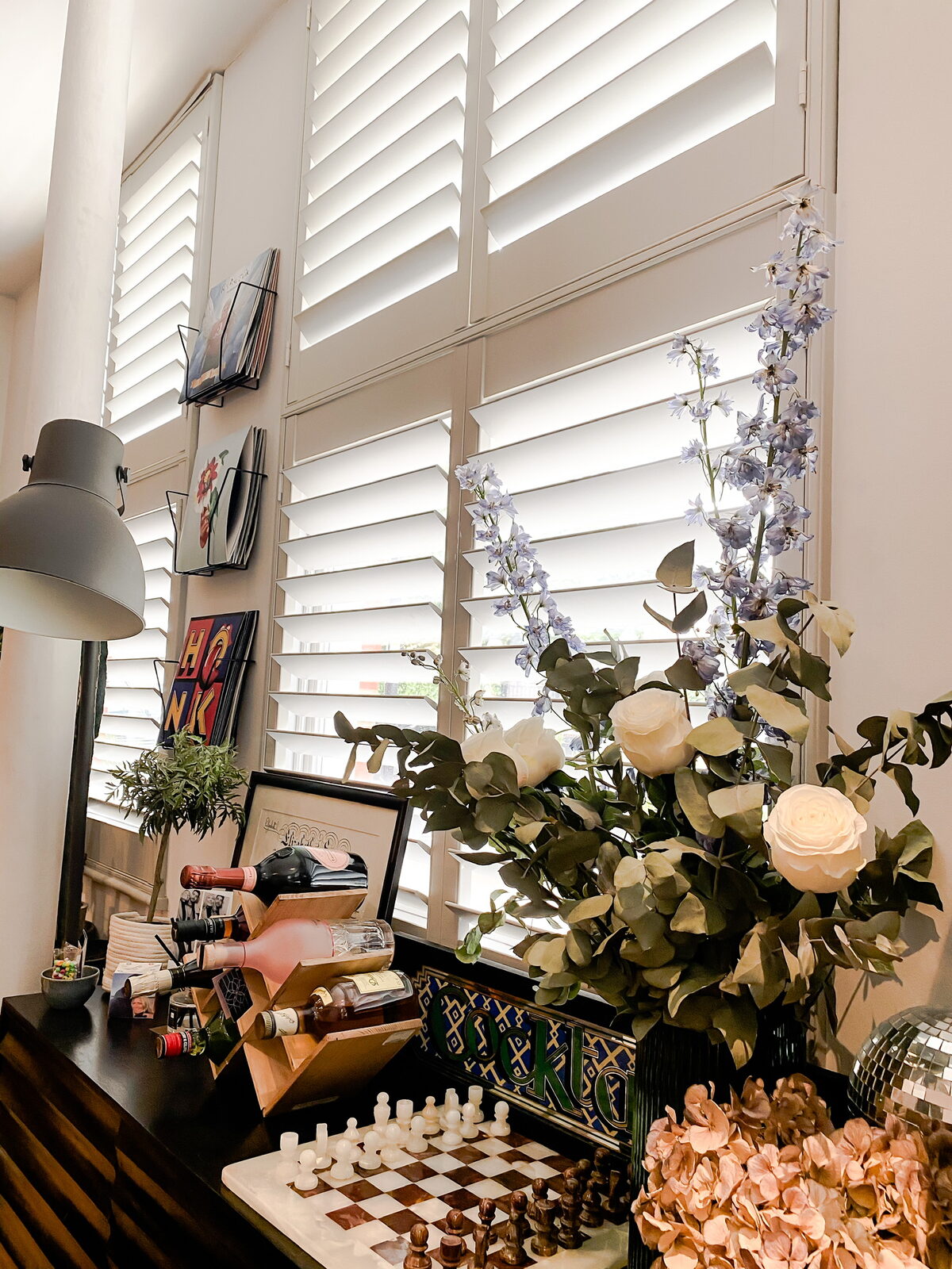 White full height shutters in a book-lined living room